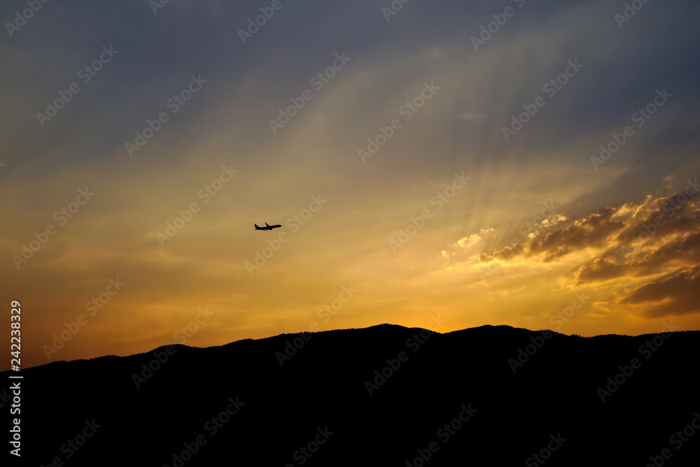 Sunset at mountain with an airplane fly pass and golden sun light