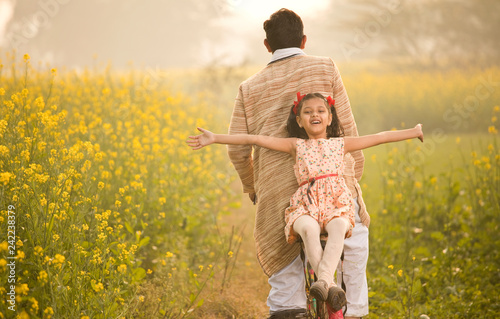 Father with daughter riding bicycle on agriculture field