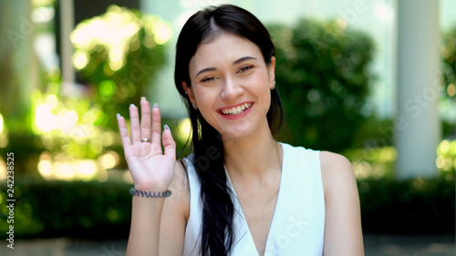 Young beautiful woman smiling while waving hand to camera