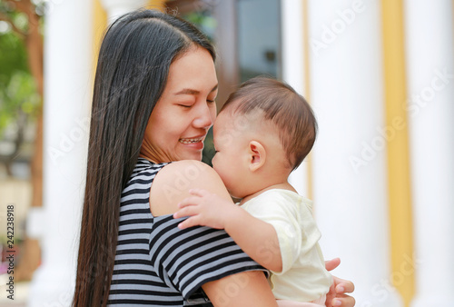 Asian mother carrying her infant. Close-up.