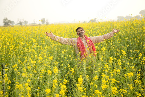 Farmer with arms outstretched in rapeseed field