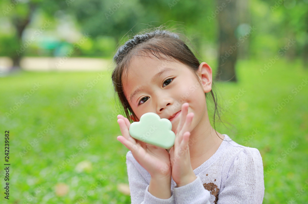 Cute little Asian child girl showing some food in her hands at green grass garden. Cute little Asian child girl showing some food in her hands at green grass garden.