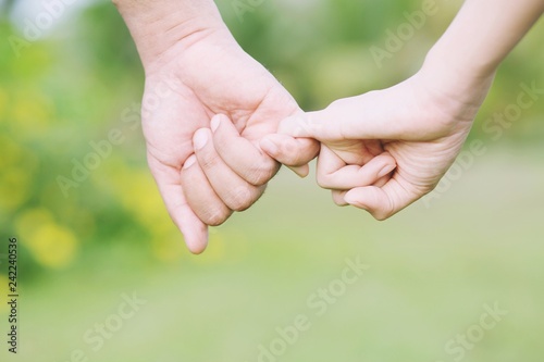 Loving Young love Woman and man holding hand Shake hand together, couple be hand in hand pinky promise or pinky swear. Happy romantic love in the garden. concept couple lover valentine day. © methaphum
