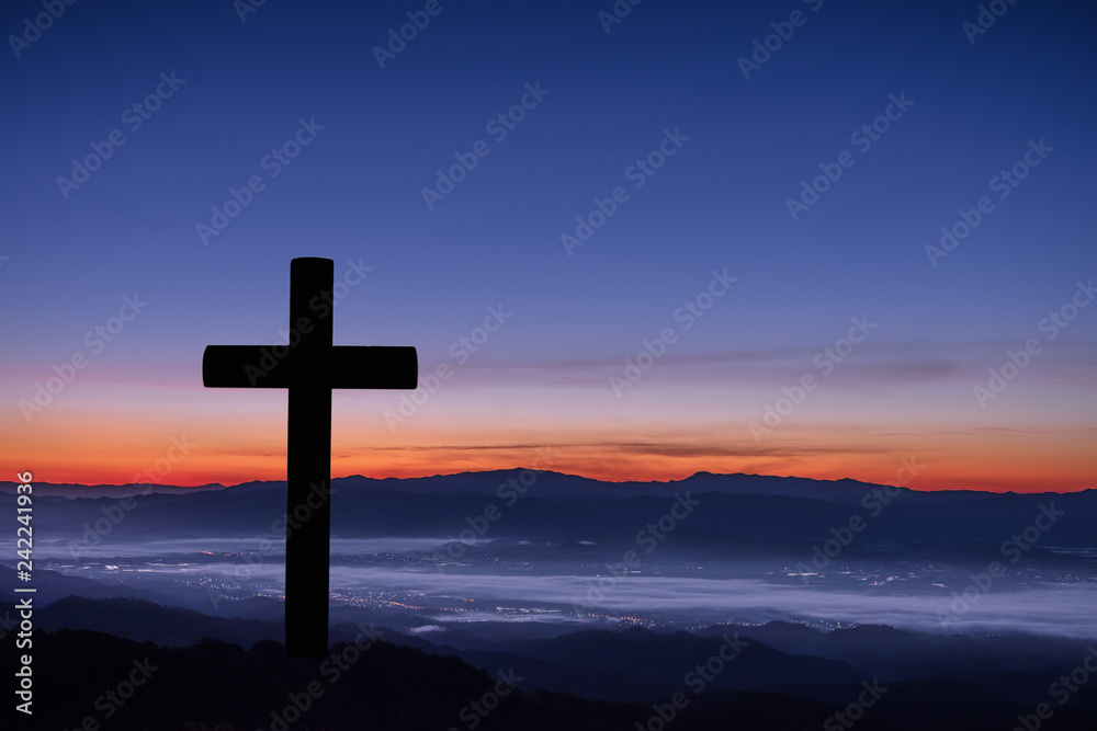 Silhouette of cross on mountain sunrise background.