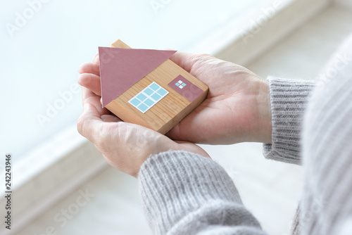 女性の手に包まれた住宅模型