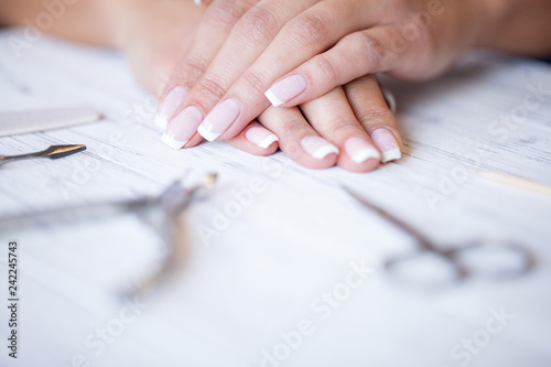 Manicure. Close up female hands situating on desk near nail tools