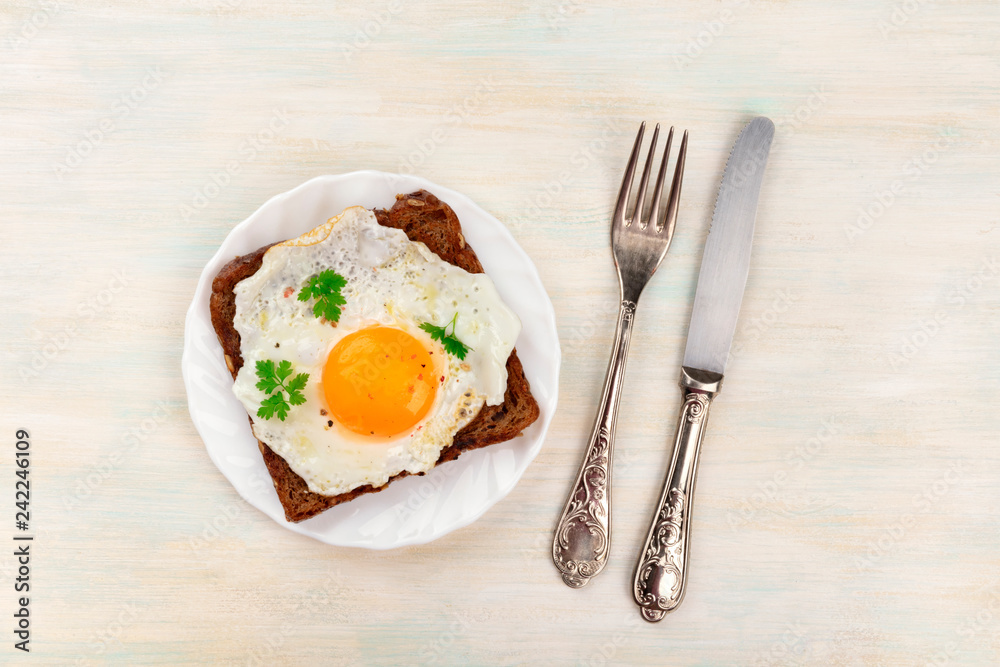 An overhead photo of an egg cooked sunny side up on a toast with a fork, knife and copy space An overhead photo of an egg cooked sunny side up on a toast with a fork, knife and copy space