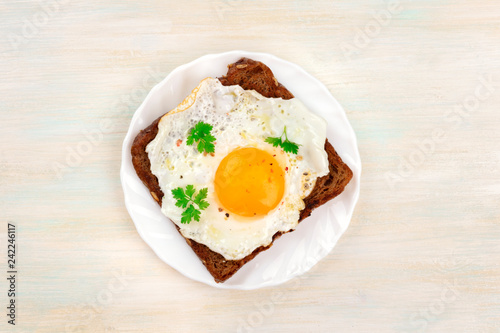 An overhead photo of an egg cooked sunny side up on a toast with a place for text