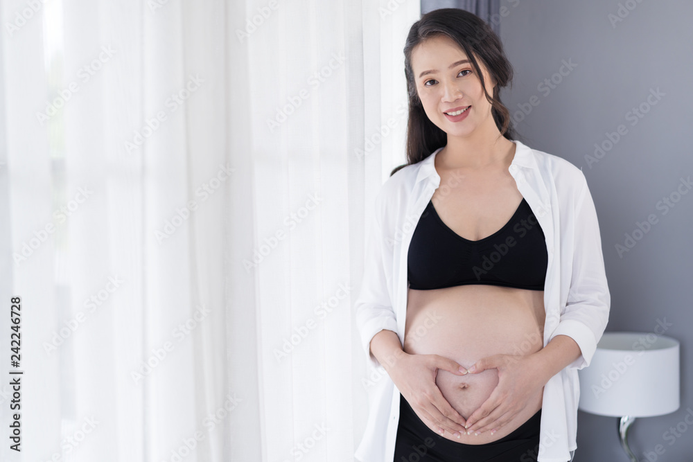 pregnant woman holding hands in heart shape on belly pregnant woman holding hands in heart shape on belly