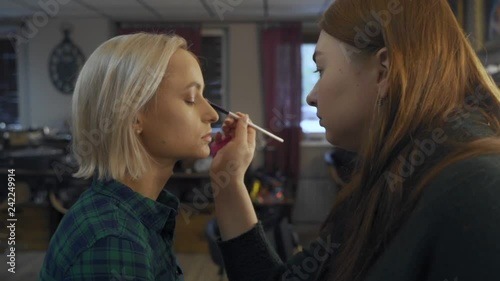 professional makeup artist making eye-makeup for young model