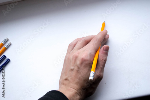 A simple pencil of orange color in the left hand on a white background