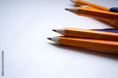 Group of simple orange pencils with blue pens close-up