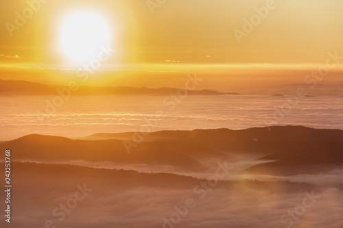 Fototapeta Naklejka Na Ścianę i Meble -  Beautiful sunset over a valley filled by fog with mountains and hills