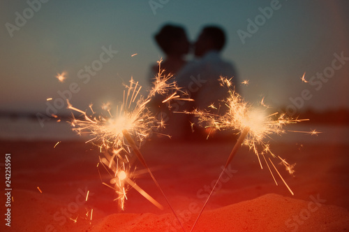Beautiful bright sparklers and on the background a kissing pair of lovers. Valentine s Day  Wedding Day or love story background