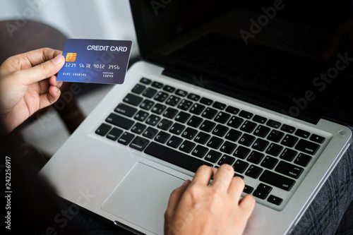 Hands holding credit card and using laptop. Online shopping. Copy space.