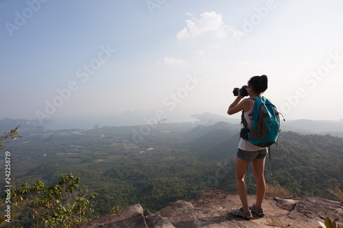 young woman photographer taking photo at mountain peak
