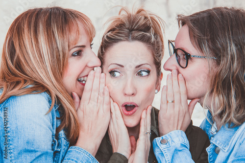 Foto Three young women with winter clothing whispering secrets