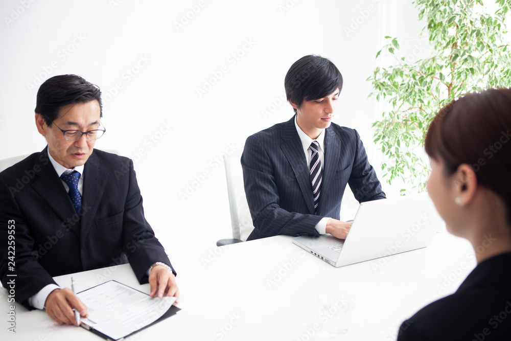 面接を受ける女性と質問を行う男性面接官二人 面接を受ける女性と質問を行う男性面接官二人