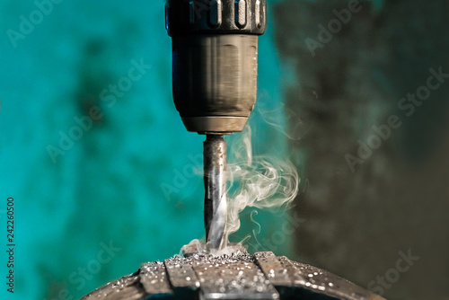 Drilling the metal with spiral drill with smoke