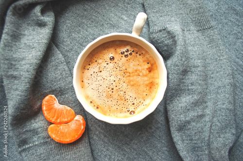 A cup of cooffee on textile grey background with tangerine. Coffee time.