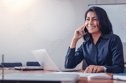 Businesswoman in black shirt talking by mobile phone in office