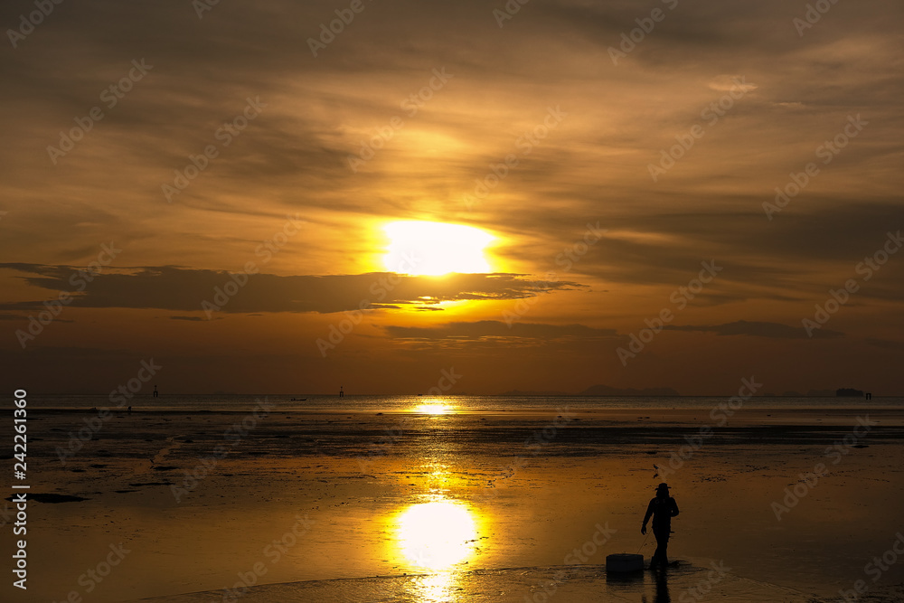 Silhouette of man walking on the beach at sunrise