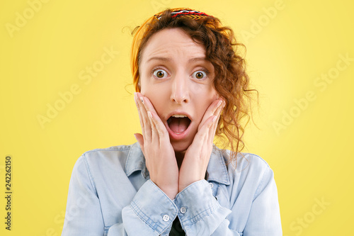 Billede på lærred Portrait of young cheerful woman in jeans shirt shocked by event
