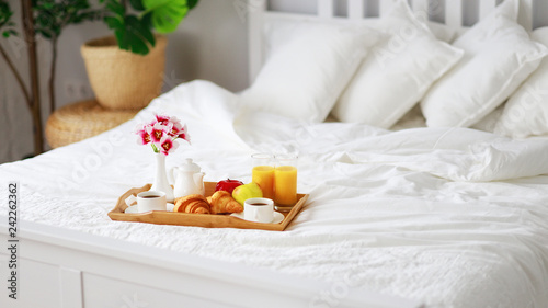 breakfast in bed of coffee, croissants, orange juice and fruit on tray