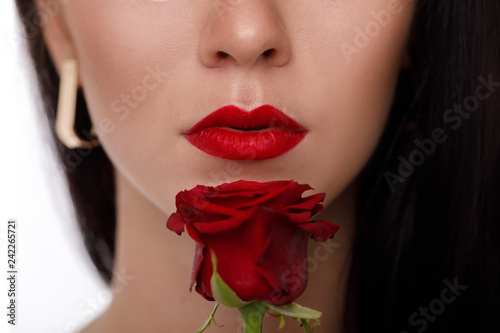 female lips with bright red makeup and red rose flower.