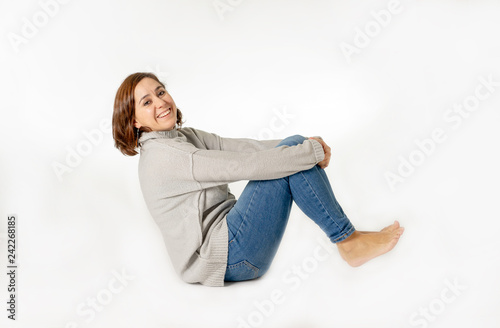 Smiling young woman sitting on floor wearing jeans and casual isolated on white and copy space