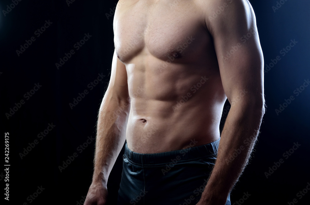 Athletic man with strained balanced chest and abdominal muscles on a dark studio background. Athletic man with strained balanced chest and abdominal muscles on a dark studio background.