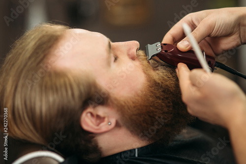 Bearded man having a haircut with a hair clippers