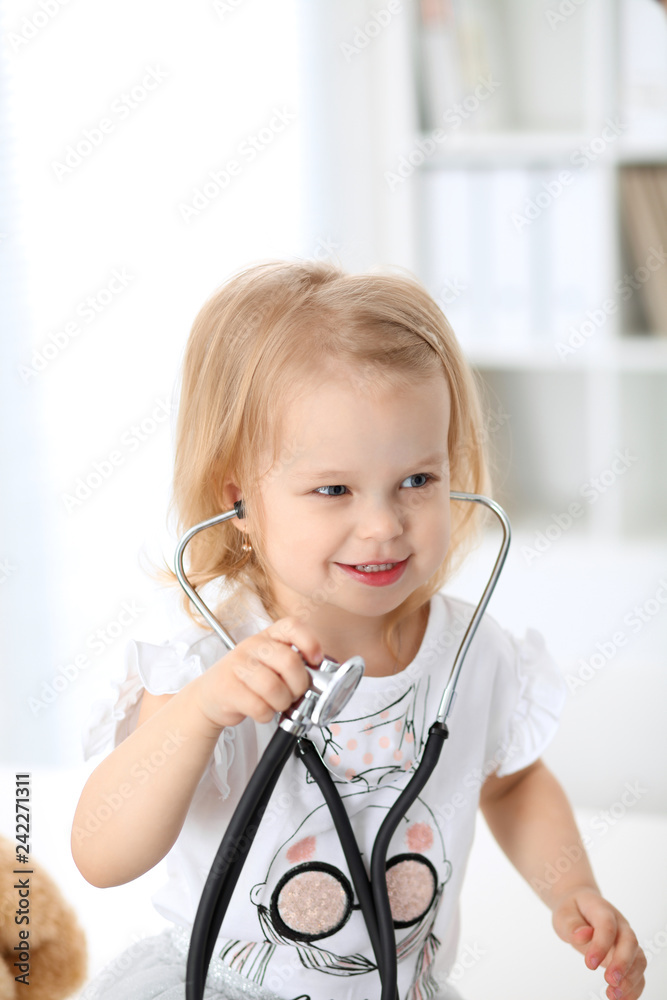 Doctor and patient baby in hospital. Little girl is being examined by pediatrician with stethoscope. Health care, insurance and help concept