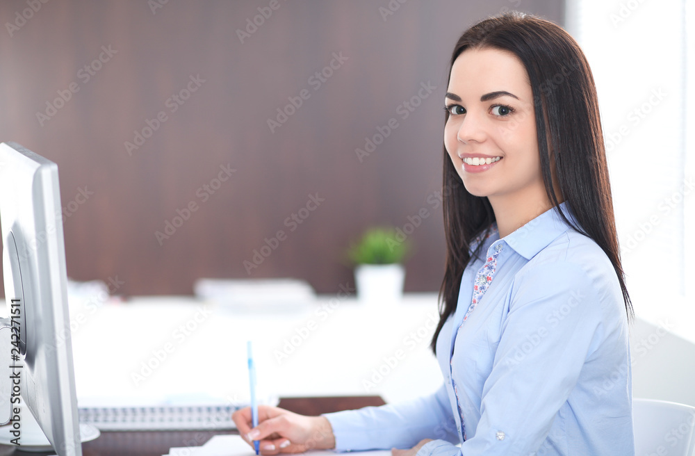 Young brunette business woman looks like a student girl working in office. Hispanic or latin american girl happy at work and too busy