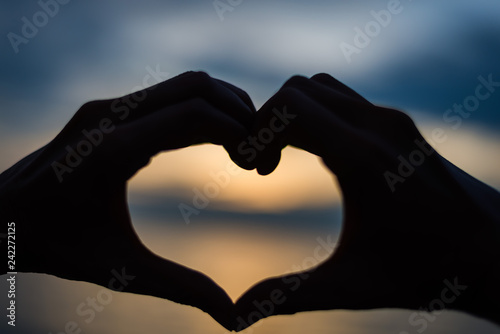 Couple doing heart shape with their hands on lake shore