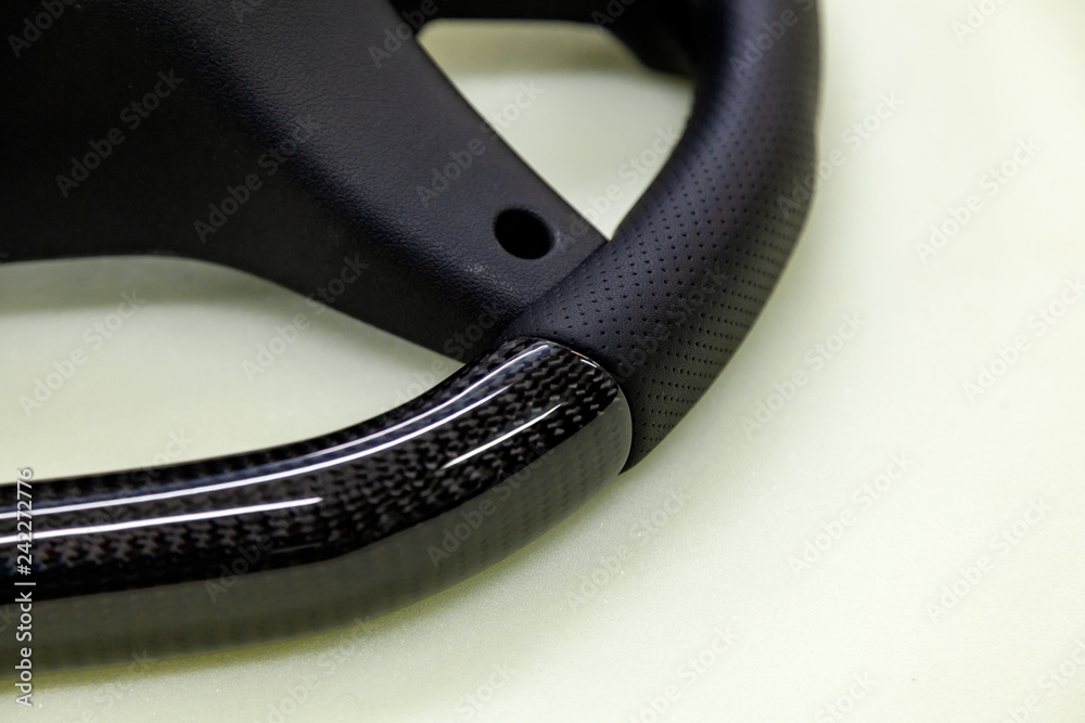 Φωτογραφία The disassembled from car steering part before installation of the equipment is a carbon black wheel with perforated genuine leather and tuning, stitched with a violet thread