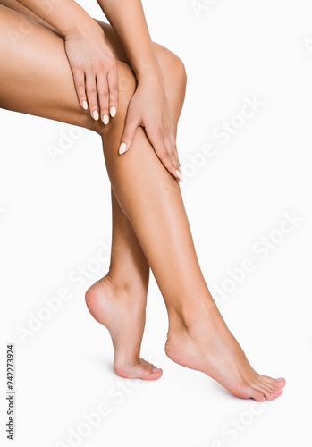 Woman applying moisturizer on her perfect legs photo