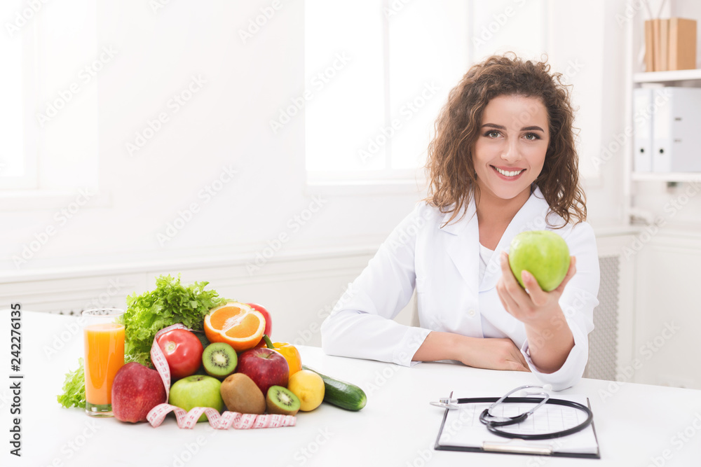 Nutritionist woman offering green apple at camera Nutritionist woman offering green apple at camera