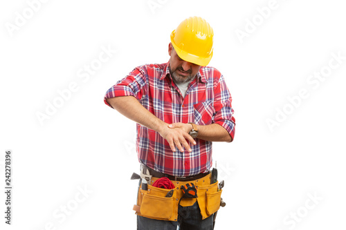 Construction worker touching injured hand.