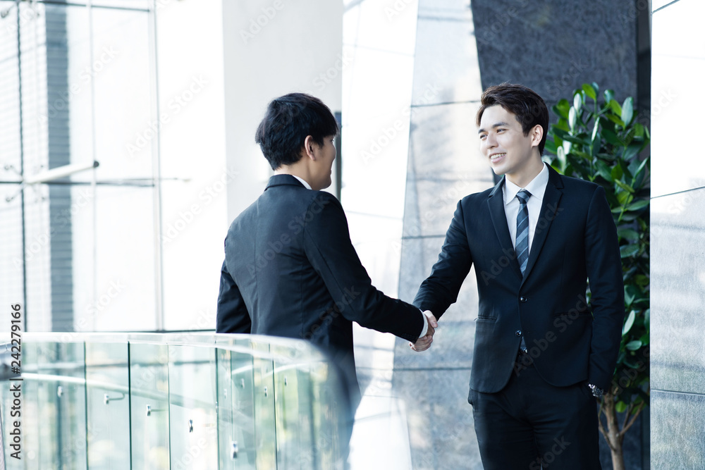 Two confident businessmen shaking hands and smiling Two confident businessmen shaking hands and smiling