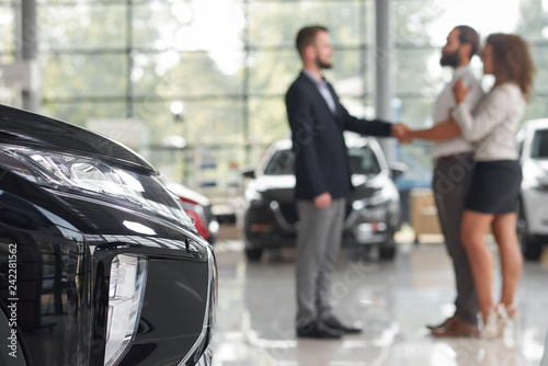 Men shaking hands, standing in car showroom.