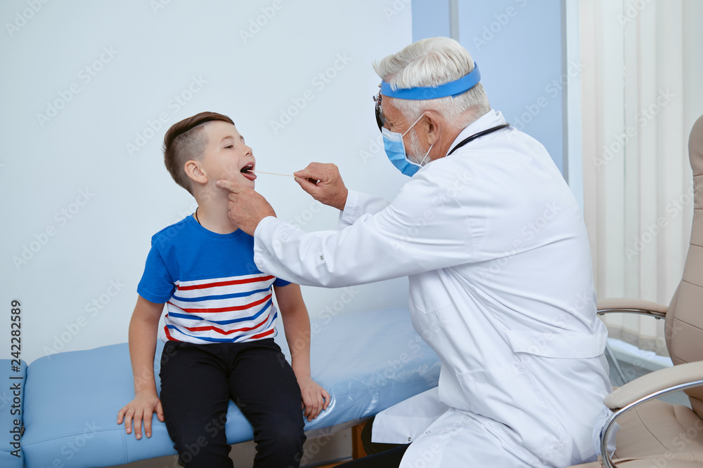 Doctor in uniform in mask treating young patient.