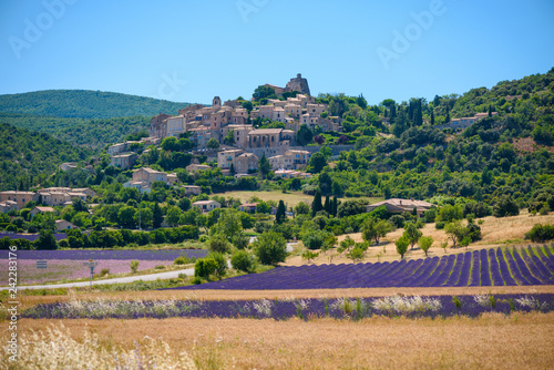 City of Saint-Saturnin-les-Apt on the hill with lavender fields in valley on summer day. Provence, France photo