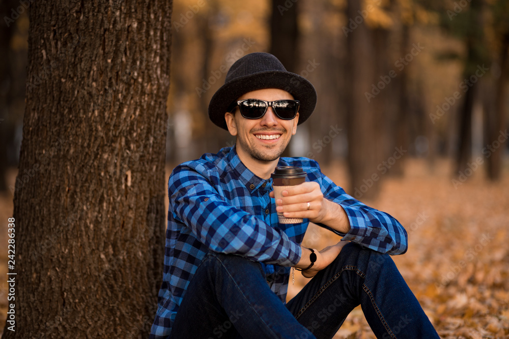 Handsome bearded man with paper cup of morning coffee walking in autumn park Handsome bearded man with paper cup of morning coffee walking in autumn park