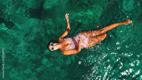 Summer image of beautiful girl swimming and lying on the back in the turquese sea water. Slim tanned body. Amazing sea landscape. Happy vacation and relaxing. Cyprus Green bay. photo