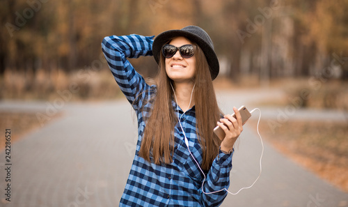 stylish woman in sunglasses listening to music in autumn park. Enjoying Music