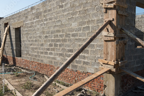 Building a house. Background of a brick house under construction. Construction beams and bricks.