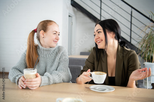 Two women are holding coffee mug. Sitting on the couch talking about the job in the morning. One cup of coffee will make the body and brain fresh.