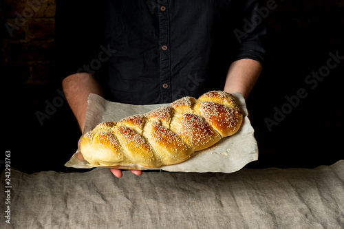 Baker holding baking tray with fresh baked challah jewish bread