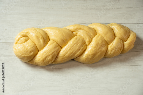 Raw loaf of challah jewish bread on wooden background. Top view flat lay.